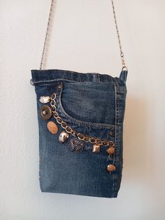 a denim purse with buttons and chains hanging from the front, on a white wall