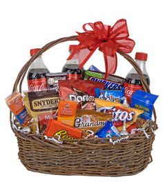 a basket filled with snacks and drinks on top of a white table next to a red bow