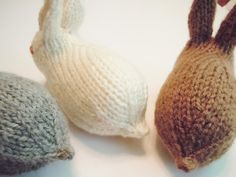 two knitted bunnies sitting next to each other on a white counter top,