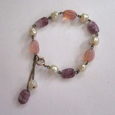 "Pastels for spring! Faux baroque pearls alternate with glass pink and blue textured beads. A pink and purple bead dangle from chains near the clasp for extra interest. Spring ring closure. Unsigned, excellent condition. This bracelet measures 7 1/2\" in length." Adjustable Pink Pearl Bracelet With Pearl Drop, Elegant Adjustable Beaded Bracelets With Dangling Beads, Vintage Pink Bracelets With Round Beads, Pink Pearl Drop Bracelet, Adjustable Pink Pearl Chain Jewelry, Elegant Adjustable Bracelet With Dangling Beads, Elegant Adjustable Bracelets With Dangling Beads, Vintage Pink Beaded Bracelet, Elegant Pink Pearl Bracelet With Colorful Beads