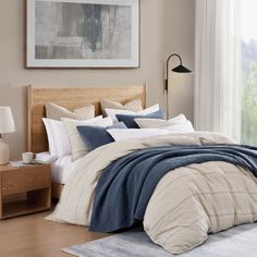 a bed with blue and white comforters in a bedroom next to a window,