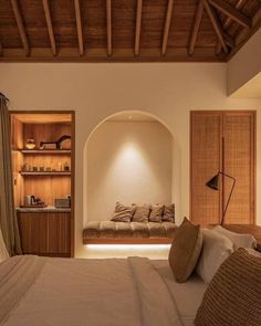 a bed sitting under a wooden ceiling next to a shelf filled with pillows and other items