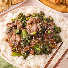 beef and broccoli on top of white rice with chopsticks