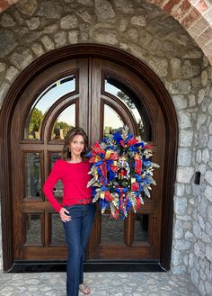 a woman standing in front of a door holding a wreath