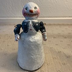 a snowman made out of cement sitting on top of a carpeted floor next to a wall