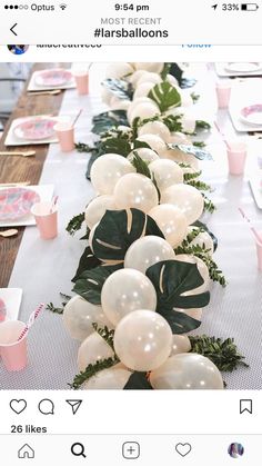 the table is set with balloons and greenery