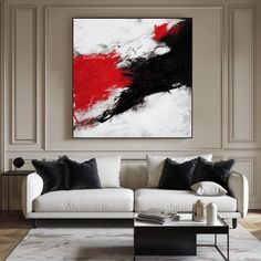 a living room with a white couch and red painting on the wall above it's coffee table