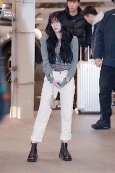 a woman with long black hair standing in an airport