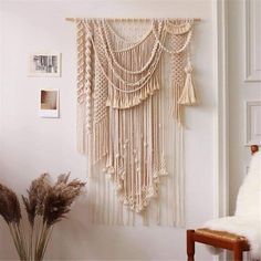 a wall hanging with tassels and beads in a room next to a chair