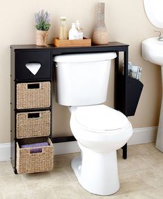 a white toilet sitting in a bathroom next to a black shelf with baskets on it