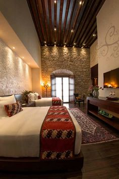 a bedroom with two beds and a stone wall in the corner, along with a rug on the floor