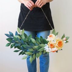 a woman is holding a flower arrangement in front of her body and wearing blue jeans