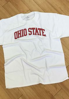 a white t - shirt with the word ohio state on it sitting on a wooden floor