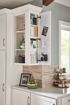 a kitchen with white cabinets and marble counter tops