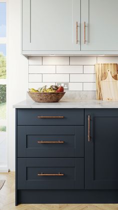 a bowl of fruit on top of a kitchen counter next to an oven and cabinets