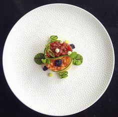 a white plate topped with fruit and veggies on top of a black table