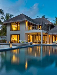 a large house with a swimming pool in front of it and palm trees on the other side