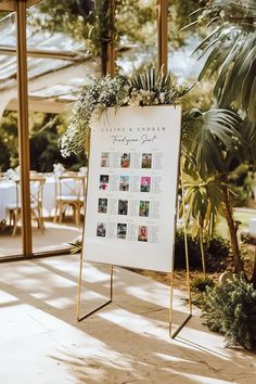 a sign that is sitting in front of a table with flowers and greenery on it