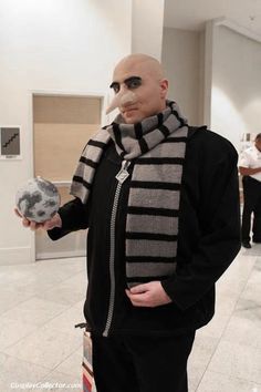 a bald man in a black jacket and scarf holding an object