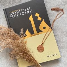 a book with a gold medallion on it next to some dried grass and a plant