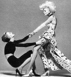 two women in black and white dresses are touching each other's legs with their hands