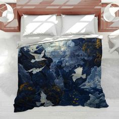 a bed covered in a blue and white comforter with two birds flying over it