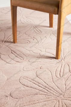 a chair sitting on top of a rug in front of a table with a vase