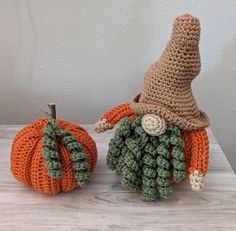 two crocheted pumpkins sitting on top of a table next to each other