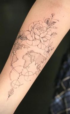 a woman's arm with flowers and a world map tattoo on the left forearm