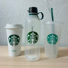 two starbucks cups and a water bottle sitting on a table