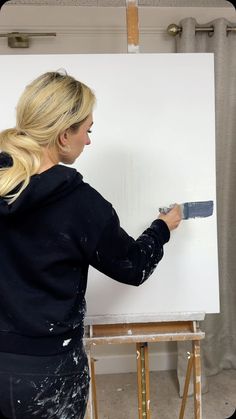 a woman is painting on a white board