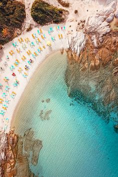 an aerial view of a beach with people laying on the sand and umbrellas in the water