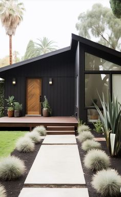 a black house with some plants in the front yard