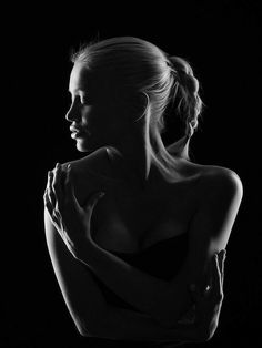 a black and white photo of a woman with her arms folded over her chest, looking to the side