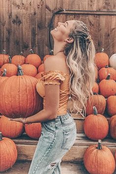 a woman with long hair standing in front of pumpkins