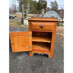 an old fashioned wooden cabinet sitting on the ground next to a mirror and trash can