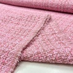 pink fabric is folded on top of a white surface with no other material in it