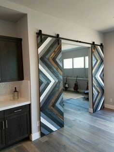 an open sliding door in the middle of a kitchen with wood flooring and white walls