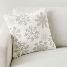 a white couch with a snowflake pillow on it's back and side