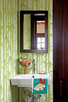 a sink and mirror in a small room with wall paper on the walls behind it