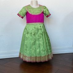 a green and pink dress sitting on top of a wooden floor