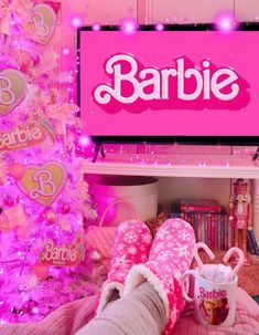 someone is laying on their bed in front of a pink christmas tree with the word barbie above them