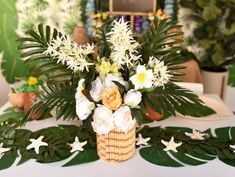 a basket with flowers and greenery is on a table in front of other decorations