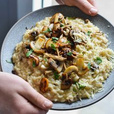 someone is holding a plate with mushroom riso