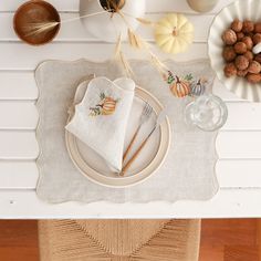 a place setting with pumpkins and white dishes