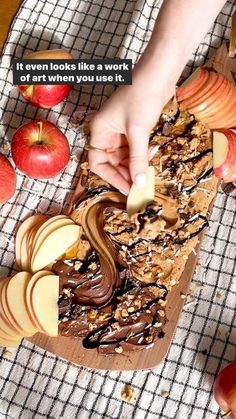 someone is decorating an apple cake with chocolate frosting and apples on the side