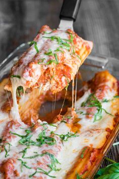 a slice of pizza being lifted from a casserole dish with cheese and herbs