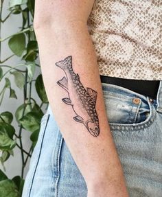 a woman's arm with a tattoo on it that has an image of a fish