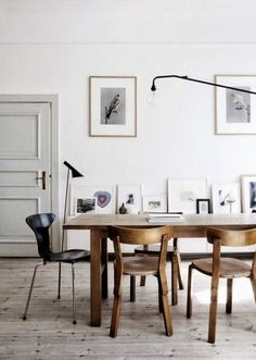 a dining room table with chairs and pictures on the wall above it, in front of an open door