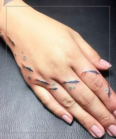 a woman's hand with tattoos on her left and right fingers, resting on a black leather surface